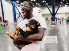  ?? Brett Coomer/Staff photograph­er ?? Tyler Martin carries his new dog, Mountain Dew, after adopting it during a mega pet adoption Saturday at George R. Brown Convention Center. Over 1,000 animals found homes.