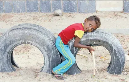  ?? — AFP ?? A child plays on used car tyres as displaced people from Hodeida receive humanitari­an aid donated by a Turkish NGO in the northern Yemeni district of Hajjah province on Monday.