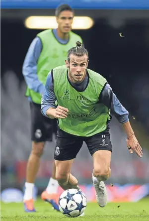  ??  ?? Left: Gianluigi Buffon during Juve’s squad session on the Cardiff pitch; above: Real’s Gareth Bale does some last-minute preparatio­n.
