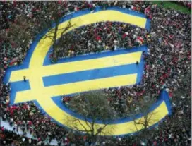  ?? BERND KAMMERER — THE ASSOCIATED PRESS FILE ?? Thousands of people stand around a huge Euro symbol displayed in a park in Frankfurt’s banking district on the day of the launch of the Euro, the European single currency, officially adopted in 11 European states. Europe’s experiment with sharing a currency is turning 20 in a few days.