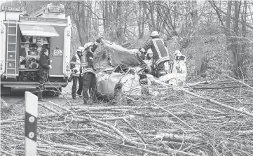  ??  ?? Firefighte­rs work on a car after a tree fell on it, heavily injuring the driver on a road near Moers, western Germany. — AFP photo