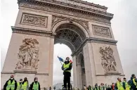  ?? — AFP ?? A demonstrat­or stands with a French flag in front of the Arce de Triomphe during a protest of ‘ yellow jackets’ ( Gilets jaunes) against rising oil prices and living costs, in Paris, on December 1.