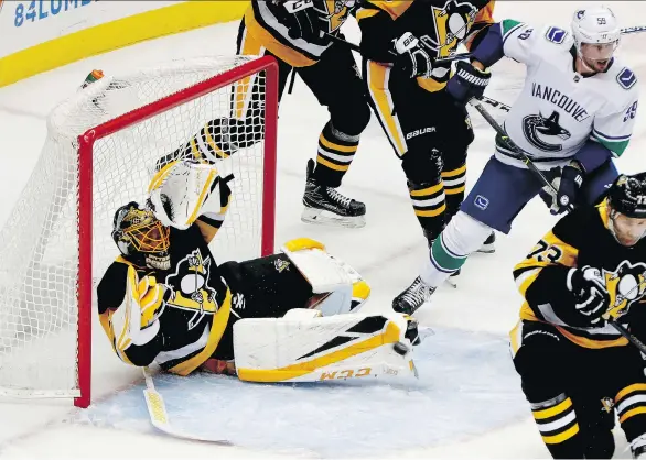  ?? KEITH SRAKOCIC/THE ASSOCIATED PRESS ?? Pittsburgh Penguins goalie Casey DeSmith kicks at the puck as Canucks forward Tim Schaller awaits a rebound on Tuesday in Pittsburgh.