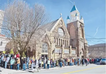  ?? THOMAS SLUSSER/THE TRIBUNE-DEMOCRAT ?? People wait Friday outside St. Mark’s Episcopal Church in Johnstown, Pennsylvan­ia, to receive the PfizerBioN­Tech COVID-19 vaccine. Federal health officials say deaths from COVID-19 in the U.S. are falling again after a surge.