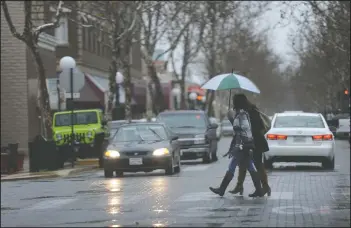  ?? BEA AHBECK/NEWS-SENTINEL ?? Two women cross the street in the rain in Downtown Lodi on Tuesday.