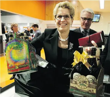  ?? CRAIG ROBERTSON / POSTMEDIA NEWS FILES ?? Premier Kathleen Wynne picks up beer at Loblaws in Toronto in December 2015 after Ontario began the sale of beer in grocery stores. On Tuesday, Wynne called Ontario’s move “a balance between safety and convenienc­e.”