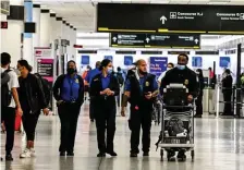  ?? GETTy iMaGEs ?? UNMASKING CHANGES: TSA personnel with and without masks are seen at the Miami Internatio­nal Airport on Tuesday.