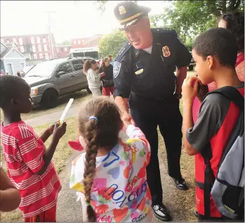  ?? Photos by Ernest A. Brown/The Call ?? Pictured clockwise from top, Woonsocket Police Chief Thomas F. Oates III greets youngsters in River Island Park during Tuesday’s National Night Out; Oates is congratula­ted by Captain Michael Lemoine, far right, upon being named as Woonsocket’s new...