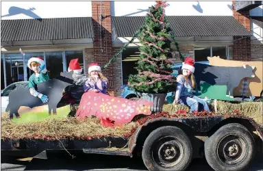  ?? MEGAN DAVIS MCDONALD COUNTY PRESS ?? Members of Cornerston­e 4-H toss candy from their barnyard Christmas float in the 2015 parade. A sign reading “Have a Moo-ey Christmas” and two cows followed the display.