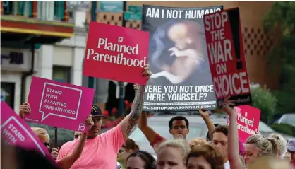  ?? — AP ?? KANSAS CITY: In this Sept. 29, 2015 file photo, people participat­e in a rally to show support for Planned Parenthood, organized by MoveOn and called “Pink Out Kansas City,” as an anti-abortion demonstrat­or stands amongst them, at the Country Club Plaza.