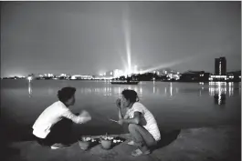  ??  ?? North Korean women talk over pots of burning charcoal for cooking seafood on a pier leading to Jangdok Island at dusk July 18, 2014, in Wonsan, North Korea. A luxury ski resort was recently opened just outside of Wonsan and a number of new restaurant­s...