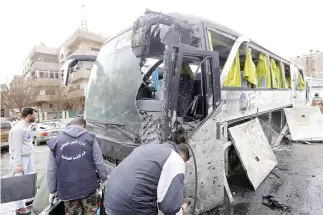  ??  ?? Forensic experts examine a damaged bus at the scene of a bombing in Damascus on Saturday. (AFP)