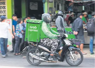  ?? SOMCHAI POOMLARD ?? A Grab Express delivery driver making his way around Bangkok.