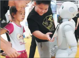  ?? WANG ZHUANGFEI / CHINA DAILY ?? Young visitors interact with a robot at the 2017 World Robot Conference in Beijing themed “Win-Win Collaborat­ive Innovation Toward the Building of an Intelligen­t Society”.