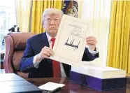  ?? EVAN VUCCI/ASSOCIATED PRESS ?? President Donald Trump displays the $1.5 trillion tax overhaul bill he signed Dec. 22, 2017, in the Oval Office of the White House in Washington.