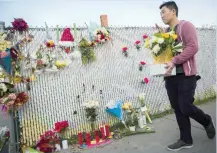  ?? AFP ?? People place flowers and notes at a makeshift memorial in Oakland, near the site of a devastatin­g fire that tore through a warehouse. —