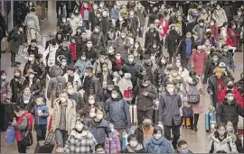  ?? Kevin Frayer Getty Images ?? PEOPLE prepare to board trains in Beijing two days before Lunar New Year. As the coronaviru­s outbreak has spread, the government has imposed travel bans.