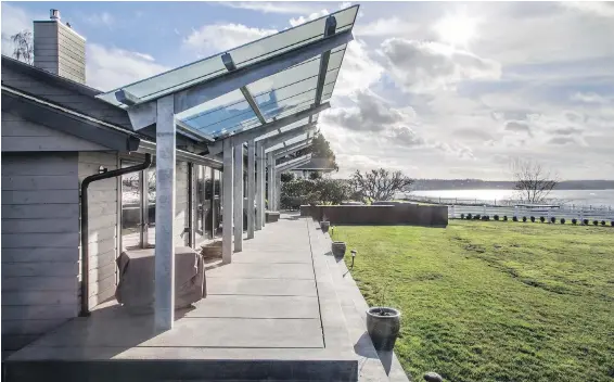  ??  ?? This 3,000-square-foot home overlooks Washington state’s Puget Sound. All along the water-facing wall are sparkling French doors to the sprawling deck, itself protected, but not darkened, by an artful overhang.