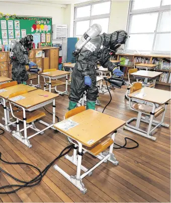  ?? PHOTO: KIM JUN-BEOM ?? Clean-up time: Military workers disinfect a classroom in Daejeon in South Korea.