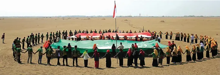  ?? DIMAS MAULANA/JAWA POS ?? KHIDMAT: Para anggota Ikatan Pelajar Nahdlatul Ulama dan Ikatan Pelajar Putri Nahdlatul Ulama melaksanak­an upacara bendera di penampunga­n luapan lumpur panas Porong. Mereka mengenang jasa para pahlawan.