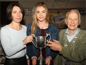  ??  ?? Gillian Kelly presents the Ann O’Keeffe trophy to Aoife Muldoon, the best female Under-17 track and field athlete, with outgoing President Nicky Cowman looking on.