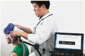  ?? — China Daily/Asia News Network ?? Gadget aid: A doctor in one of Shanghai’s rehab centres fitting a VR helmet on a patient to test his addiction level.