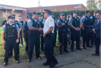  ?? SAM CHARLES/SUN-TIMES PHOTOS ?? Grand Central District Cmdr. Anthony Escamilla (in white) shakes the hands of district officers at a roll call held near where 2-year-old Julien Gonzalez was shot to death last weekend.