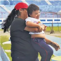  ??  ?? Una maestra carga a uno de los niños que fue parte del evento deportivo de ayer en el Estadio “Mágico” González.
