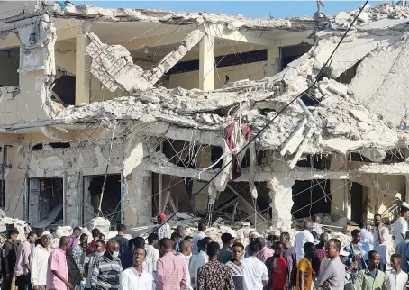  ?? Reuters ?? Civilians gather on Monday near the ruins of a building at the scene of an explosion along K5 street in Mogadishu, Somalia.