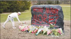  ?? PAUL SANCYA / AP ?? A student leaves flowers at The Rock, a freshly painted landmark on the grounds of Michigan State University, in East Lansing, Mich., on Tuesday. A gunman killed five students and wounded others Monday at Michigan State. Police said early Tuesday that the shooter killed himself.