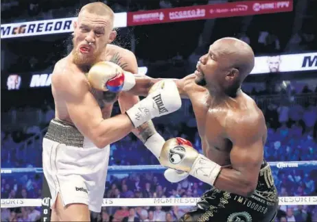  ?? AFP ?? Floyd Mayweather Jr (right) throws a punch at Conor McGregor during their super welterweig­ht bout at the TMobile Arena in Las Vegas on Saturday.