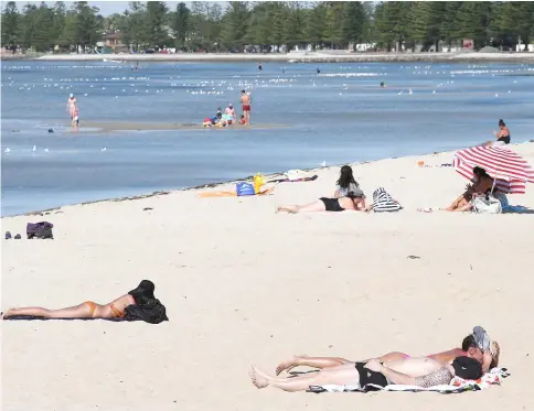  ??  ?? People sunbathe at Altona beach in Melbourne, Australia. — Reuters photo