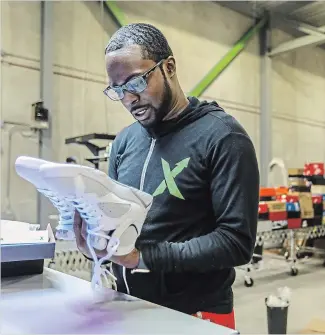  ?? KIMBERLY P. MITCHELL TNS ?? Antonio Gray, 29, of Detroit, worked as a sneaker salesperso­n for six years before becoming a authentica­tor at StockX, where he looks over a pair of Jordans at the new authentica­tion centre in Detroit on Tuesday.