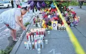  ?? ?? A woman lights a candle at a makeshift memorial outside of Tops market on May 15 in Buffalo, New York.