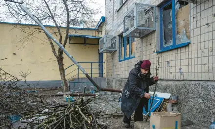  ?? EVGENIY MALOLETKA/AP ?? Local resident Emilia Budskaya breaks dead tree branches to help heat her basement Saturday in the front-line city of Vuhledar, Ukraine.