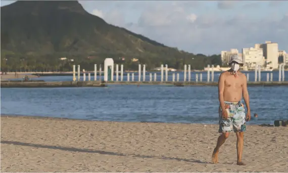  ?? MARCO GARCIA/REUTERS ?? A beachgoer walks down Honolulu’s Waikiki Beach during the pandemic on Tuesday. “Even in a recession I think the demand to travel will be high, if only because people feel restless and cooped up,” writes Tyler Cowen. But there’s a problem — destinatio­ns like Hawaii may not be so keen about seeing tourists, Cowen adds.