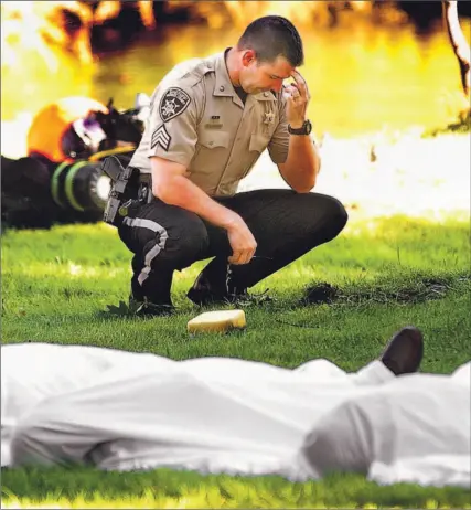  ?? T.J. HOOKER/THE POST STAR/ AP ?? Sgt. Steven Stackdale of the Warren County Sheriff’s Office kneels near the bodies of victims of yesterday’s boating tragedy. Twenty-one seniors died when the Ethan Allen overturned on Lake George in the Adirondack Mountains in upstate New York.