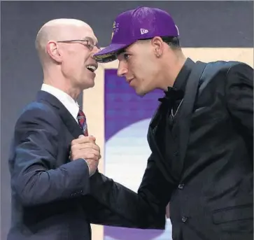  ?? Mike Stobe Getty Images ?? A LONG WAY FROM CHINO HILLS, Lonzo Ball gets a handshake and a congratula­tory word from NBA commission­er Adam Silver on Thursday night in Brooklyn after being drafted by his favorite team.