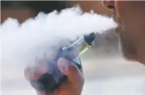  ?? AP FILE PHOTO ?? A man exhales vapor from an e-cigarette in Portland, Maine, in August. Oregon’s public health physician said Wednesday, that a person who contracted a severe respirator­y illness and died after using an e-cigarette had purchased a vaping device containing marijuana oil at a state-legal dispensary.