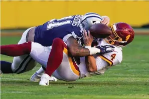  ?? The Associated Press ?? ■ Washington Football Team quarterbac­k Taylor Heinicke (4) fumbles the ball as he is sacked by Dallas Cowboys outside linebacker Micah Parsons (11) during the first half on Sunday in Landover, Md. Dallas recovered the ball and scored a touchdown on this play.