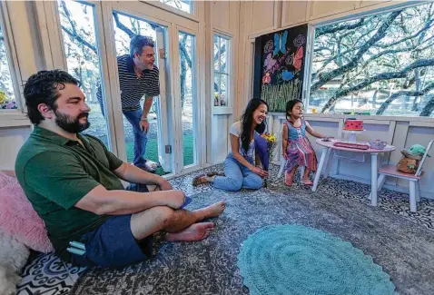  ?? William Luther / Staff photograph­er ?? Dave Peters, second from left, of D. Michael Designs peeks into the playhouse he constructe­d for 3-year-old Lila Romo. Lila’s parents, Victor and Malisa, decided to build the playhouse for their daughter after a visit to England, where Lila was enthralled by a community playhouse.