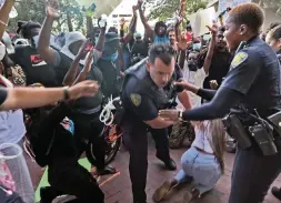  ?? Herald staff ?? Cellphone video of Sunday’s rally in Fort Lauderdale that was circulatin­g on social media shows the officer — who was identified by the department as Steven Poherence — in a crowd of protesters, with other officers nearby.