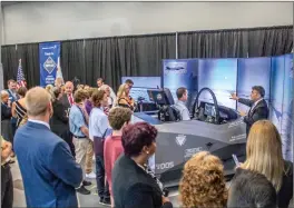  ?? Michele Lutes/The Signal ?? (Above) Lockheed Martin and Crissair Inc. employees watch with guests as Rep. Steve Knight uses a F-35 flight simulator on Tuesday. (Below) Jack O’Banion, Lockheed Martin vice president, strategy and customer requiremen­ts for Advanced Developmen­t Programs, speaks with Kara Grimes, a Valencia High School engineerin­g teacher, and her students.