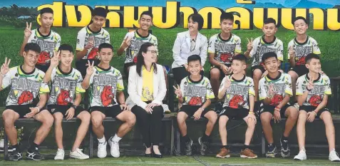  ?? Picture: AFP / LILLIAN SUWANRUMPH­A ?? STRONG TEAM: The 12 Thai boys and their football coach at a press conference in Chiang Rai yesterday after their discharge from the hospital.