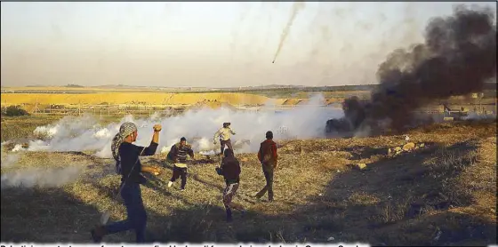  ?? AFP ?? Palestinia­n protesters run from tear gas fired by Israeli forces during clashes in Gaza on Sunday.