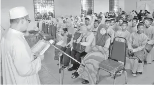  ?? — Gambar Bernama ?? TAKLIMAT: Khairudin (kiri) selaku ketua jurunikah memberi taklimat kepada 18 pasangan Orang Asli yang bernikah pada Program Perkahwina­n Perdana di Kampung Pasir Linggi, Pos Lebir, dekat Gua Musang, semalam.