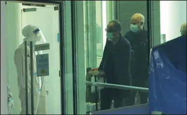  ?? ASSOCIATED PRESS ?? Passengers arriving on the flight from Singapore are processed Thursday by staff in protective clothings and directed towards a covered walkway to a separate exit from the airport terminal in Wuhan in central China’s Hubei province.