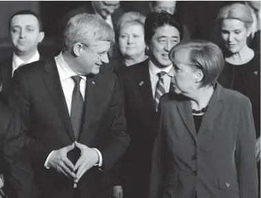  ?? SEAN KILPATRICK/ THE CANADIAN PRESS ?? Prime Minister Stephen Harper talks with German Chancellor Angela Merkel as they take part in the official photo at the Nuclear Security Summit in The Hague, Netherland­s, on Tuesday. Harper will travel to Germany Wednesday for two days.