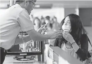  ?? CHOE JAE KOO/AP ?? A South Korean quarantine officer checks the body temperatur­e of a passenger in August 2014 at Incheon Internatio­nal Airport in South Korea after a deadly outbreak of the Ebola virus in West Africa.