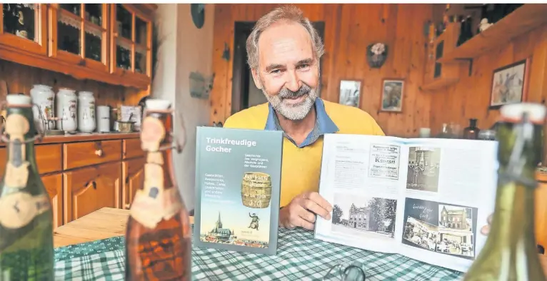  ?? FOTO: MARKUS VAN OFFERN ?? Autor Hans-Joachim Koepp mit dem Teil zwei der „Trinkfreud­igen Gocher“und einigen stilechten Bierflasch­en von anno dazumal.